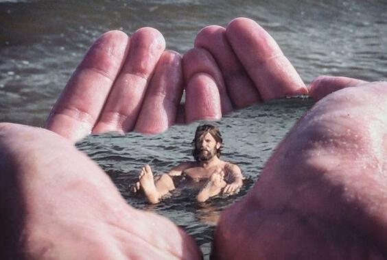 Ein Mann schwimmt in Wasser, welches von zwei großen Händen zurückgehalten wird.