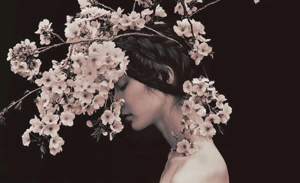 Frau mit geschlossenen Augen unter blühenden Zweigen