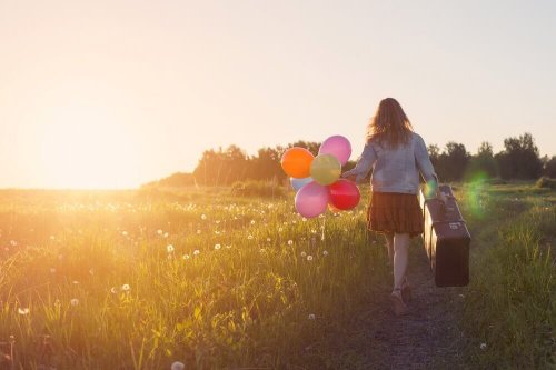 Frau mit Koffer und Ballons in ihren Händen