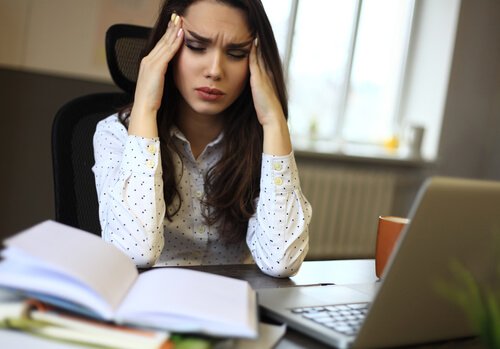 Frau im Büro hat Kopfschmerzen