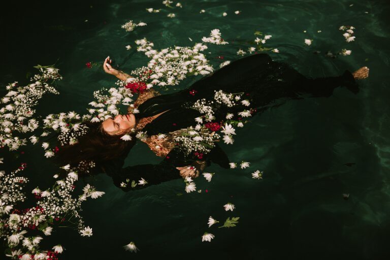 Frau treibt im Wasser zwischen Blumen