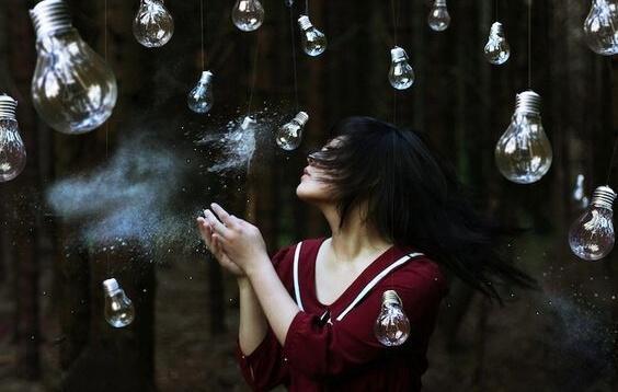 Über einer jungen Frau hängen lauter Glühbirnen.