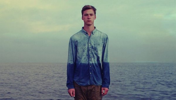 Junger Mann vor dem Meer, das Wasser steht ihm bis zum Bauch