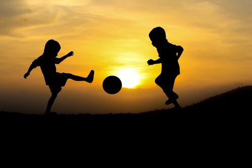 Kinder spielen im Sonnenuntergang Fußball