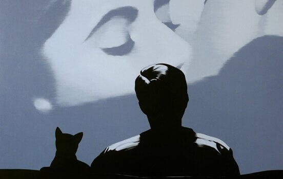 Ein Mann und eine Katze sitzen im Kino.