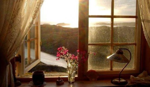 Foto aus einem Zimmer heraus mit offenem Fenster, draußen sieht man eine Landschaft