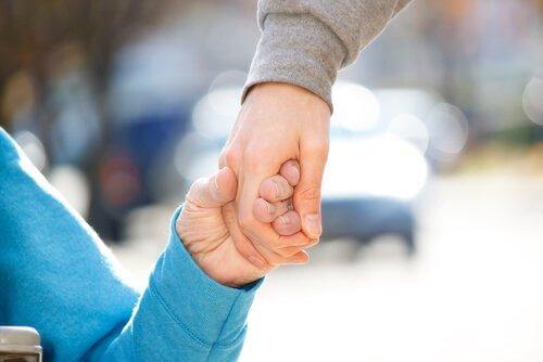 Eine Person hält die Hand einer älteren Person.