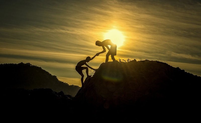 Person hilft einer anderen auf einen Berg