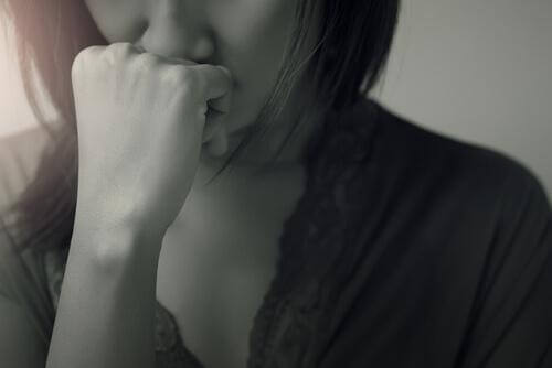 Schwarz-Weiß-Foto einer Frau, die sich die Faust vor den Mund hält und verzweifelt ist