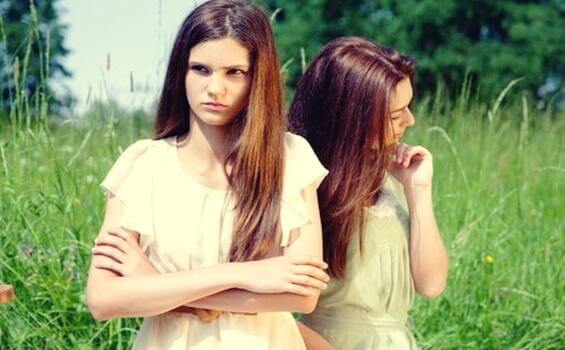 Junge Frau steht im Gras und schaut verärgert