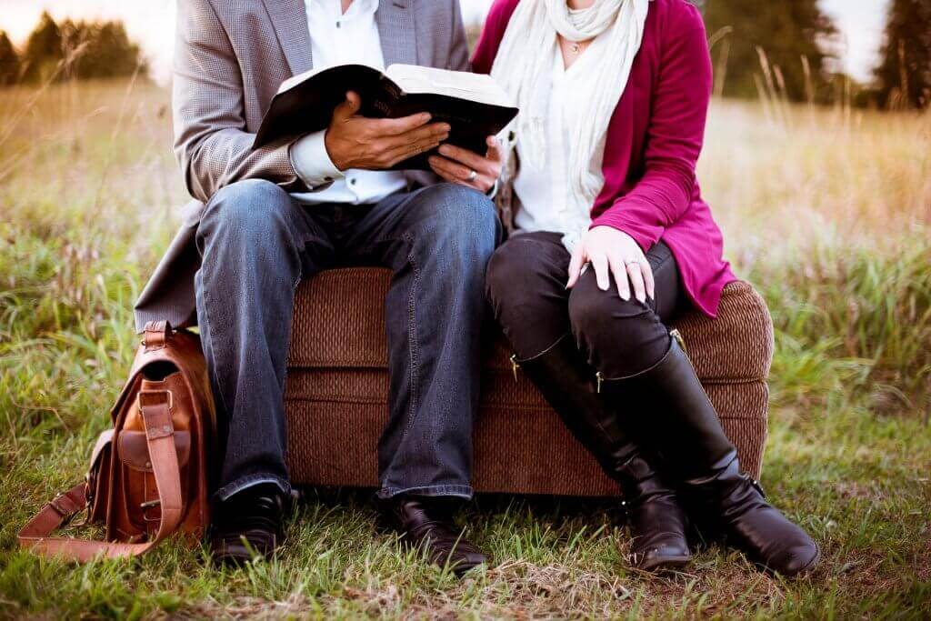 Paar sitzt auf einem Koffer und schaut in ein Buch