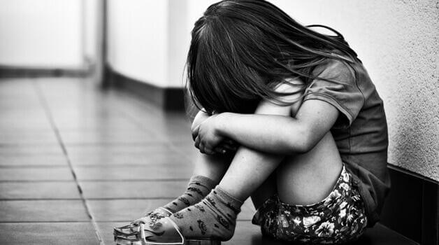 Schwarz-Weiß-Bild eines trauriges Mädchens am Boden