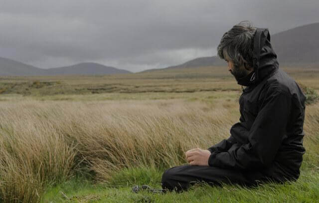 Mann sitzt einsam an einem Feld