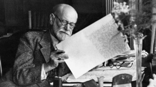 Freud sitzt an seinem Schreibtisch.