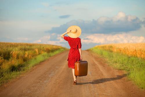 Frau mit Koffer auf einem Weg