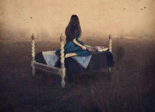 Frau sitzt auf Bett und schaut in die Ferne