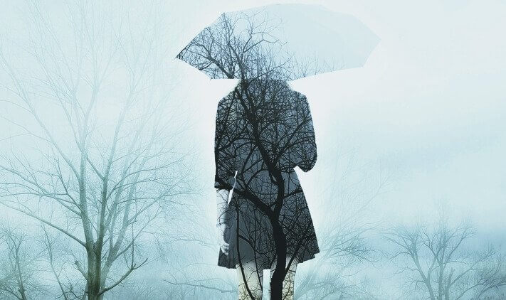 Frau mit Regenschirm in kaltem Winterwald