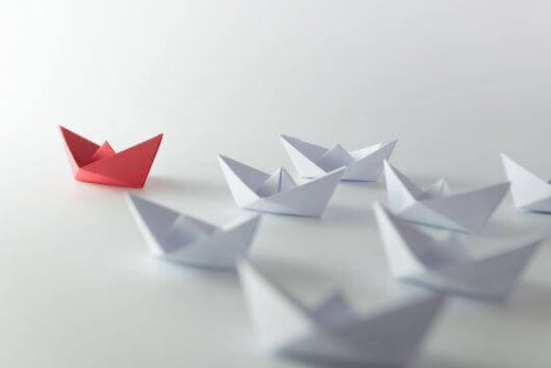 Rotes Papierschiff vor weißen Papierschiffen