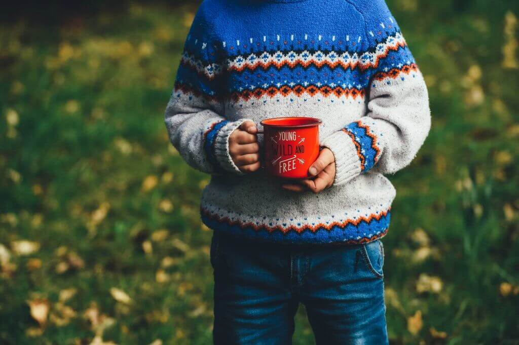 Ein Junge hält eine Tasse.