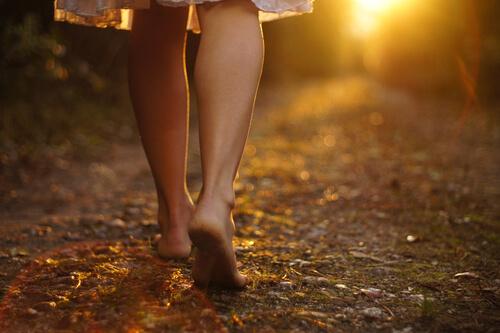 Frau läuf auf einem Weg voller Blätter bei Sonnenuntergang
