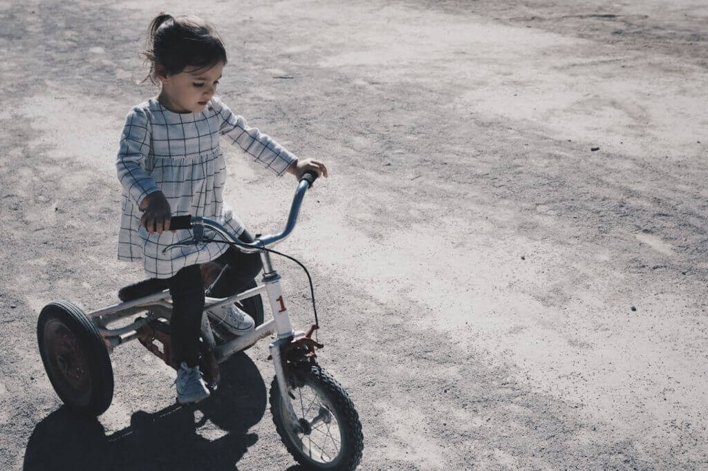 Das Beste gegen Übergewicht bei Kindern ist Bewegung. Ein Mädchen fährt Dreirad.