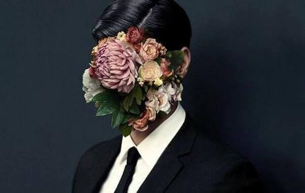 Mann im Anzug mit pomadigem Haar trägt statt eines Gesichtes ein Blumenarrangement.