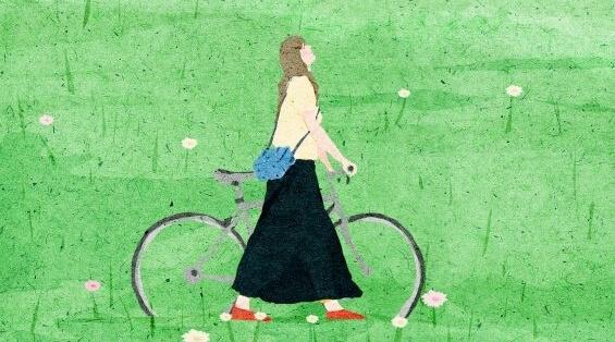 Frau schiebt ihr Fahrrad über eine grüne Wiese