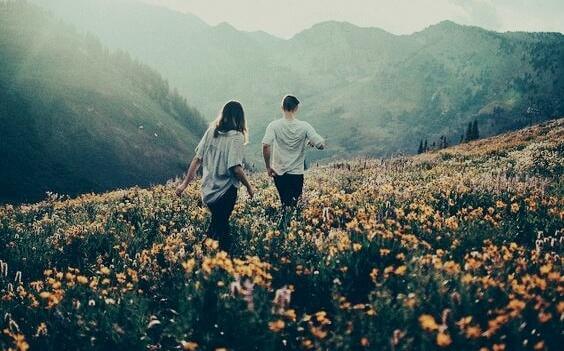 Paar geht auf Blumenwiese in den Bergen
