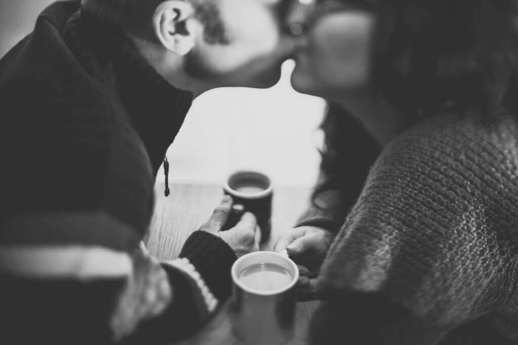 Paar küsst sich und trinkt zusammen Kaffee