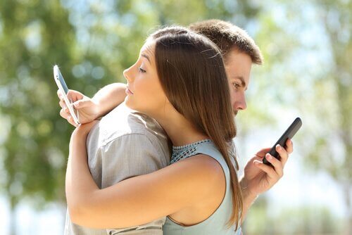 Partner umarmen sich, während sie auf ihre Telefone schauen