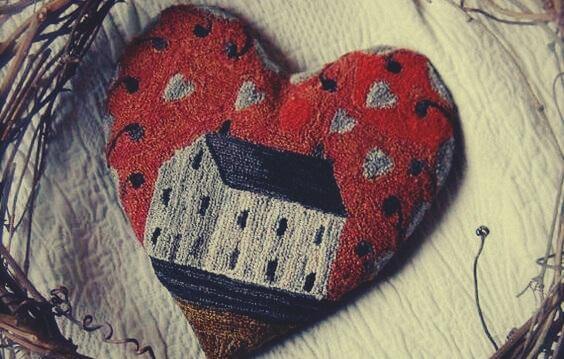 Ein rotes Herz aus Stoff mit einem Haus darauf