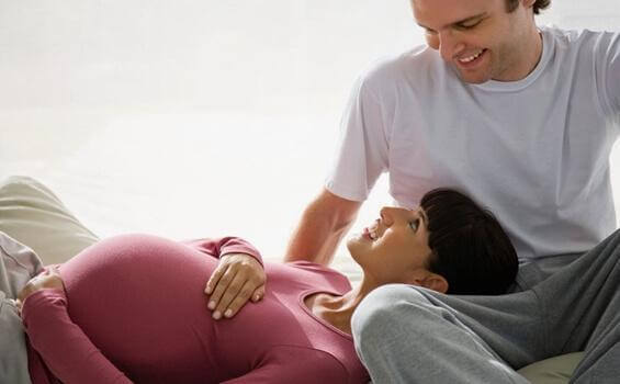 Eine schwangere Frau und ihr Mann blicken sich glücklich an. 