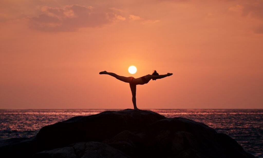 Frau macht Yoga bei Sonnenuntergang