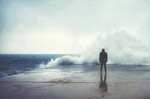Mann schaut auf eine große, brechende Welle