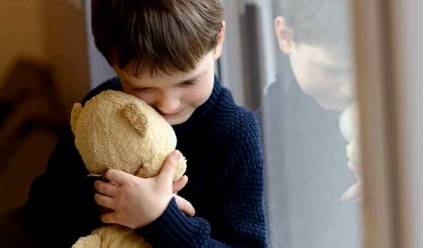 Knabe kuschelt mit Teddybär