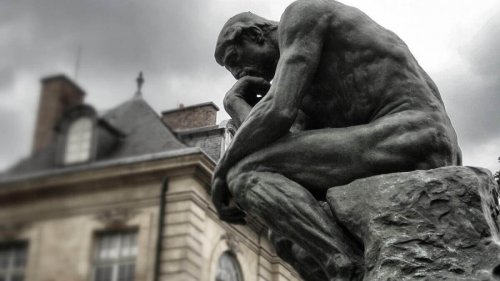 Eine Statue eines Menschen in denkender Pose.