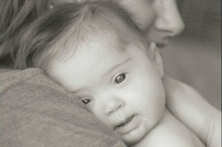Baby mit Down-Syndrom wird von seiner Mutter gehalten
