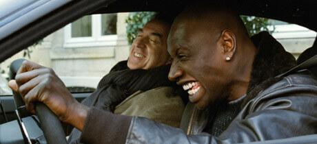 Driss und Philippe sitzen lachend im Auto