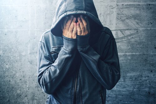 Ein Mann in Kapuzenpulli verdeckt sein Gesicht. 