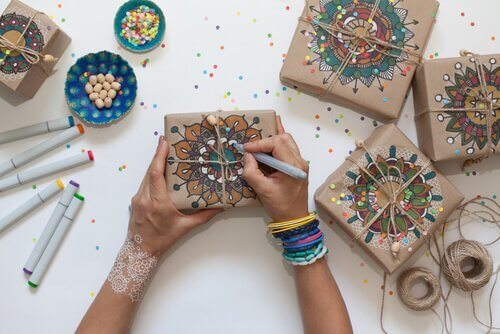 Zwei Hände malen Mandalas auf Geschenke