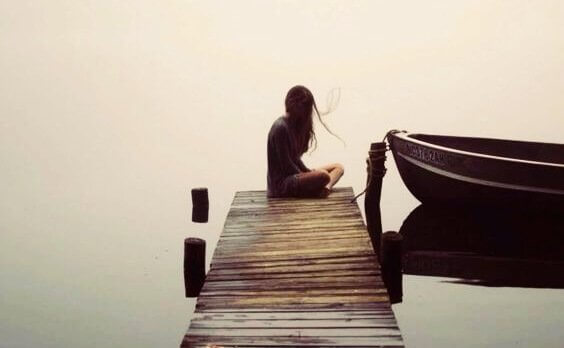 Ein Mädchen sitzt allein an einem Steg