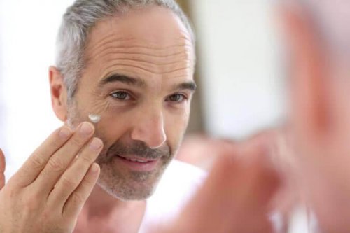 Ein Mann in seiner Midlife-Crisis trägt etwas Creme in sein Gesicht auf.