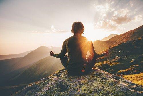 Ein Mann sitzt auf einem Berg in einer Meditationspose.