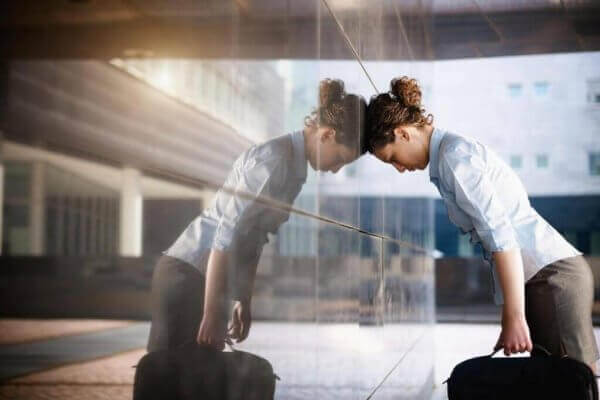 Eine verzweifelte Frau lehnt ihren Kopf gegen eine Glaswand