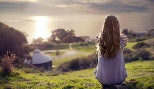 Frau blickt einen Hang hinab auf einen See