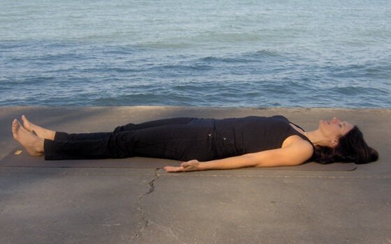 Eine Frau liegt am Meer und wendet Entspannungstechniken zum Einschlafen an