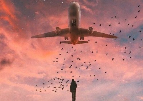 Ein Mann blickt auf ein Flugzeug, das über ihm fliegt.