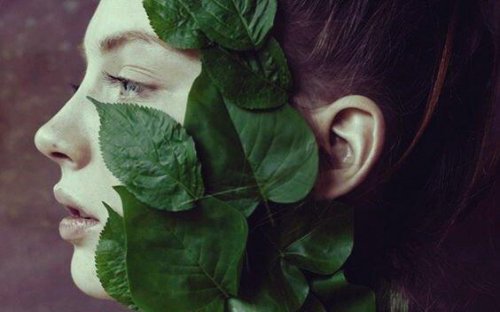 Das Gesicht einer Frau ist bedeckt mit Pflanzenblättern und Apathie.