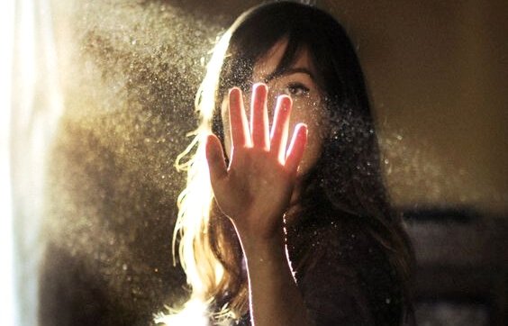 Frau betrachtet ihre Hand im Lichtstrahl
