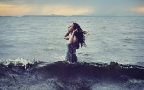 Mädchen lauscht stehend im Wasser.